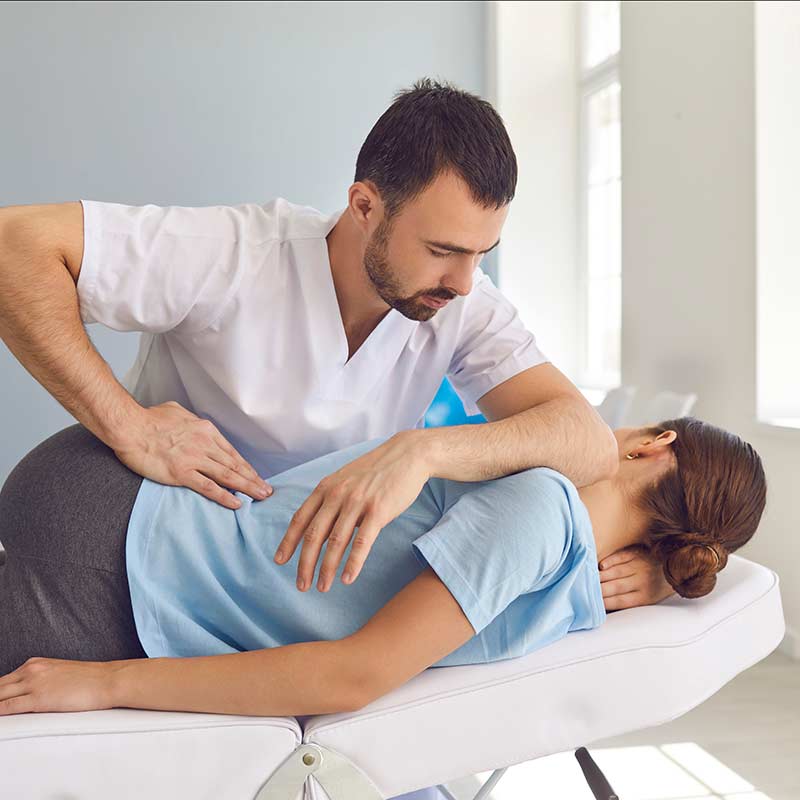 Chiropractor treating a young woman on a medical couch